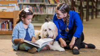 Little girl reading to a dog