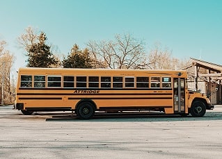 School bus on street with trees and sky in background