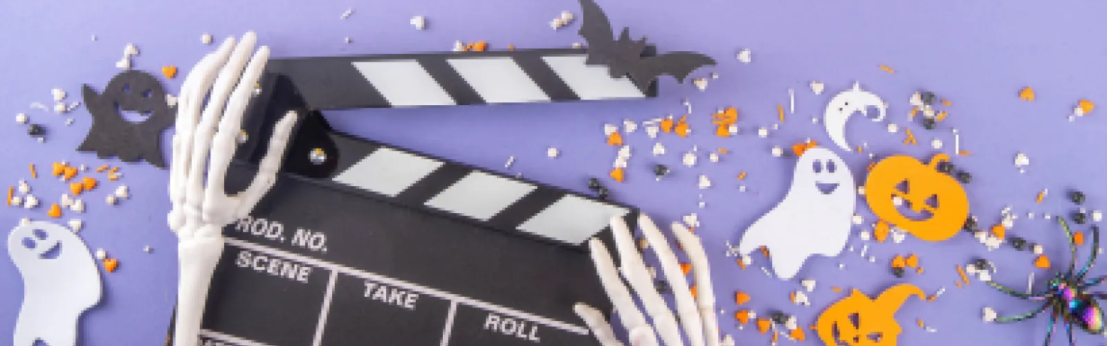Plastic skeleton hands holding movie props surrounded by halloween decor