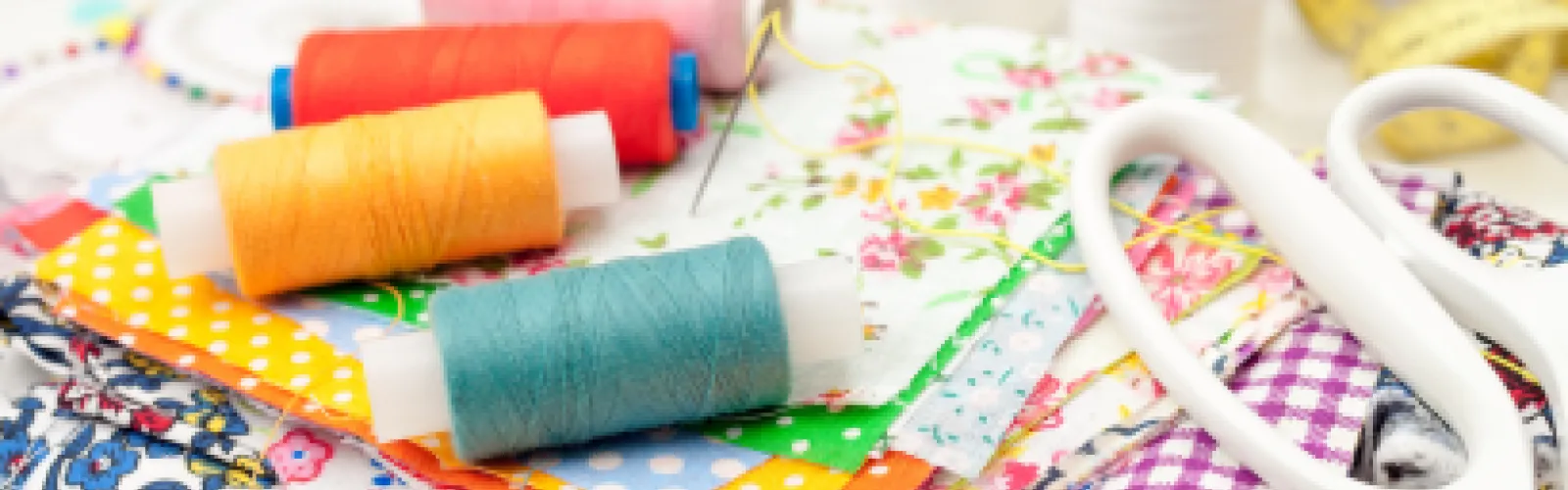 Miscellaneous sewing supplies including thread, scissors, and fabric.