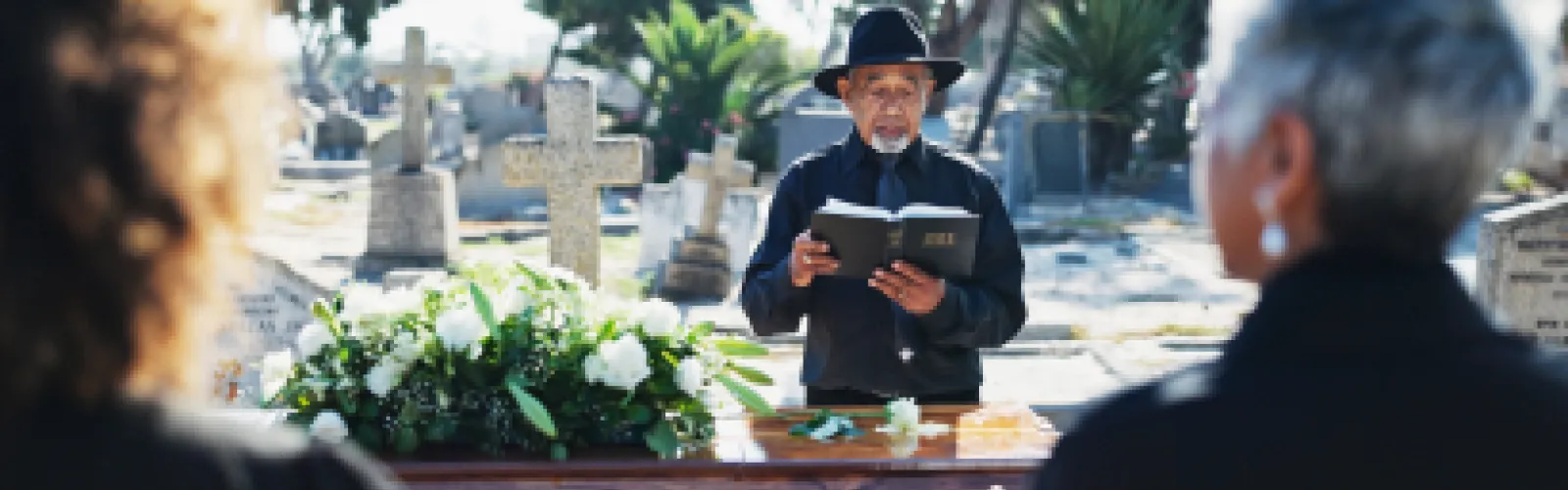 Burial with a casket, priest, and bible.