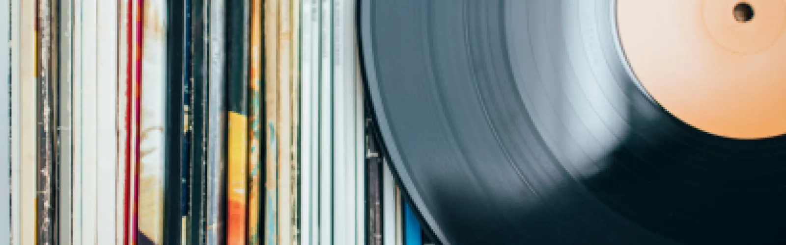 A vinyl record laying on a row of records in their sleeves