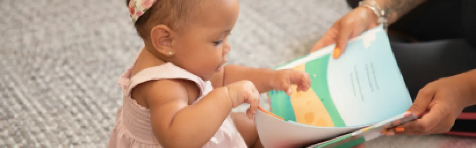 baby girl reading a book with mom