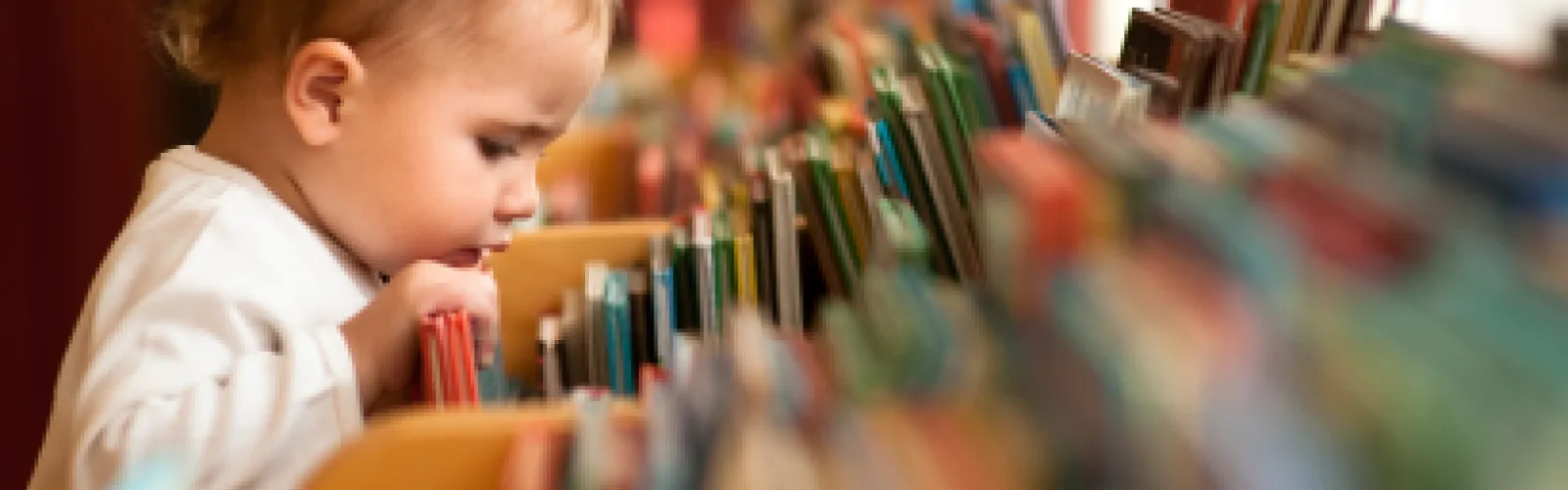 child looking for something in the children books bin